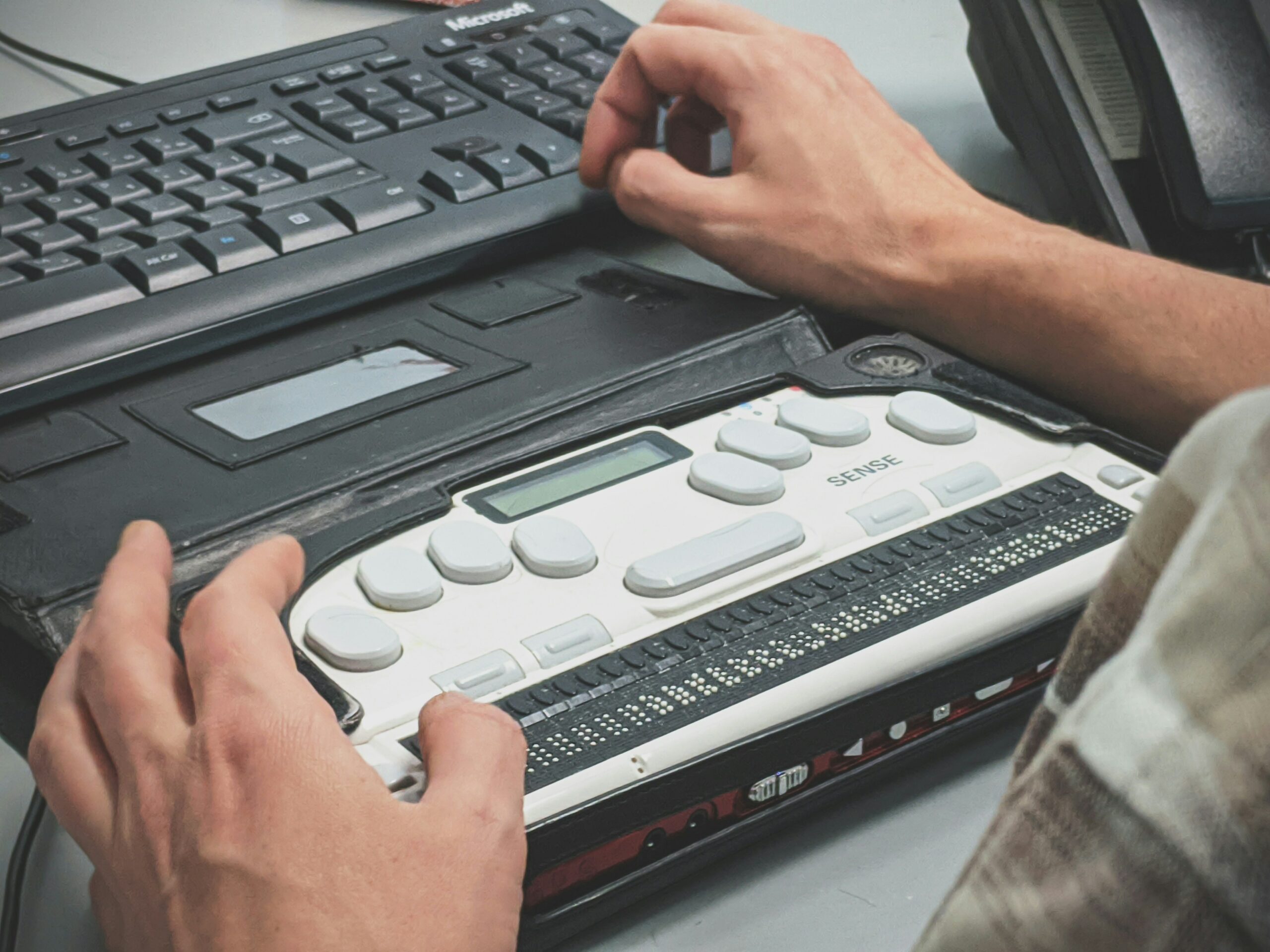 A user using a braille machine with a computer.